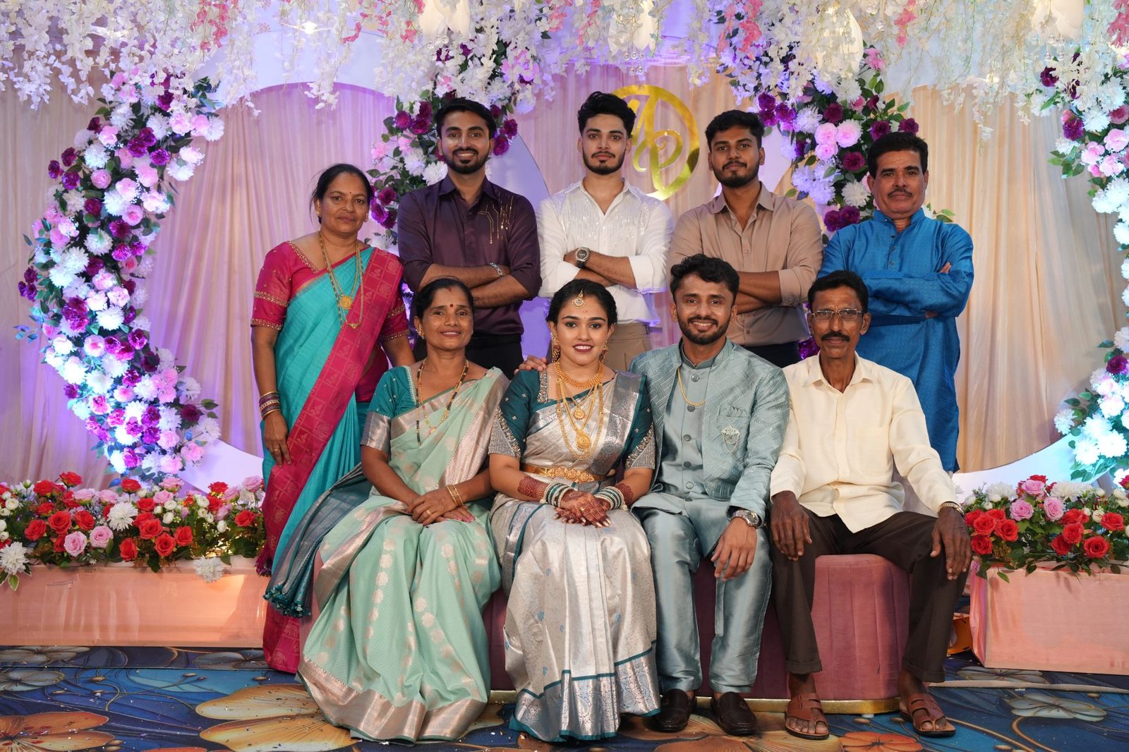 Pawan and Manisha seated with both families in front of the floral engagement stage